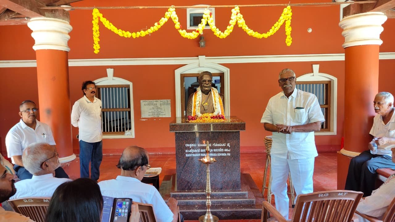 A speaker addressing participants beside the poet's statue